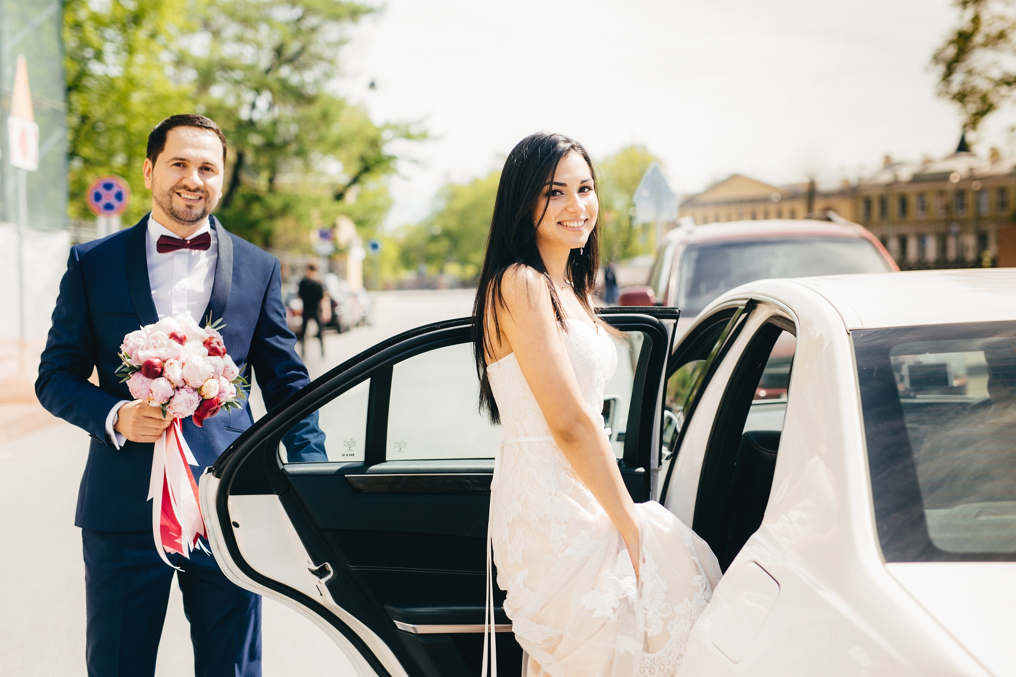 Portrait of newlywed couple sit in car after ceremony, have happy expression